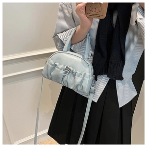 Detail view of light blue pleated dumpling bag with adjustable strap and top handle design