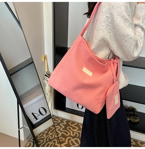 Detail of pink corduroy tote bag featuring a vertical texture and small matching pouch