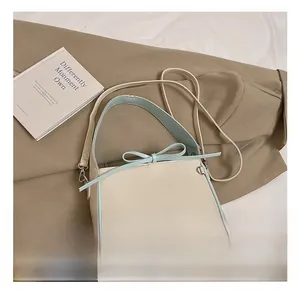 Détail du sac seau blanc crème avec nœud bleu et fine bandoulière élégante