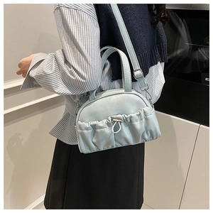 Detail of mint green ruched crossbody bag with silver hardware and pleated leather texture