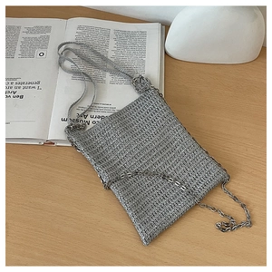 Close-up of silver woven handbag with metallic texture and slender metal chain strap