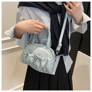 Detail view of light blue gathered cloud handbag with adjustable shoulder strap and top handle