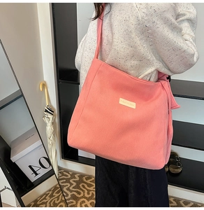 Detail of pink corduroy tote showing texture and woven brand label on shoulder bag