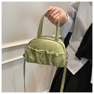 Detail view of the pleated pocket and drawstring on a sage green crossbody shell bag