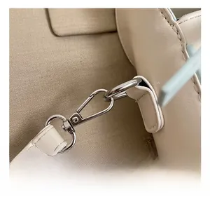 Détail du crochet métallique argenté et de la bandoulière sur le sac seau crème