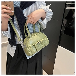 Detail of light green pleated handbag showing the silver metal buckle and soft PU texture