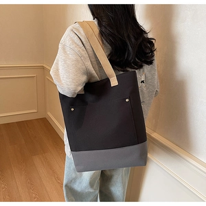 Canvas tote bag with dual-tone design and gold rivets shown in a lifestyle setting