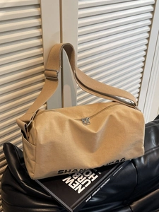 Large khaki canvas messenger bag with adjustable shoulder strap and cylinder shape