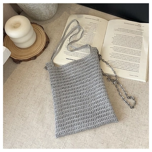 Detailed close-up of silver-grey woven knit crossbody bag with metallic chain strap