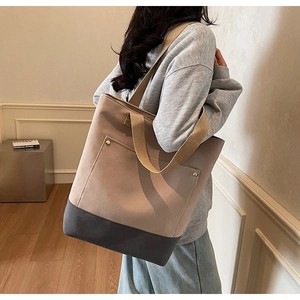 Close-up of khaki and grey canvas tote bag with metal rivets and wide shoulder straps