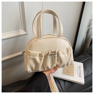 Detail of a creamy white pillow handbag with ruffled design and silver drawstring hardware