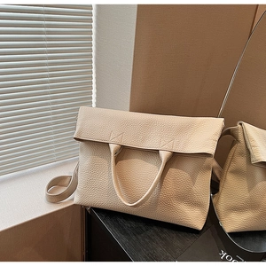 Detail einer beigen Tragetasche aus genarbtem Leder mit elegantem Faltklappen-Design