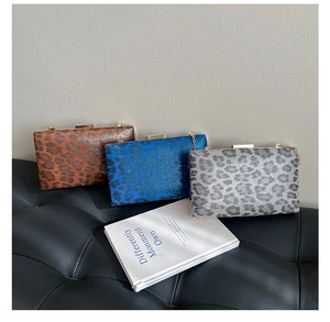 Dettaglio di pochette con stampa leopardata in marrone e blu con sottili tracolle a catena