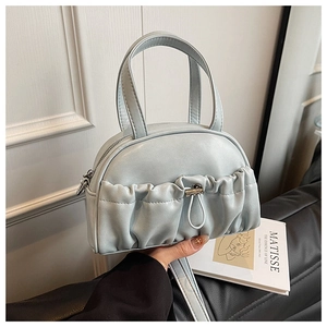 Detail of light blue faux leather handbag featuring pleated front pocket and metal drawstring