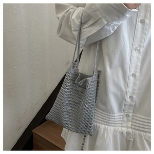 Detail of silver woven mini bucket bag with metallic chain strap and textured handles