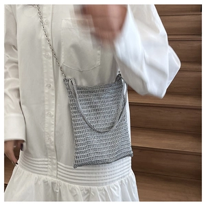 Close-up of silver woven crossbody bag texture with delicate metal chain strap