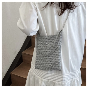 Detail of silver woven crossbody bag with metallic chain strap and textured crochet finish