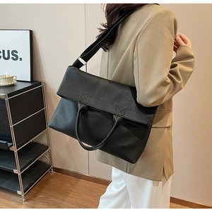 Detail der schwarzen Shopper-Tasche mit Litschimuster, Klappverschluss und Schultergurt