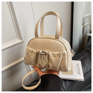 Detail of a creamy white handbag featuring soft pleated pockets and silver metal hardware