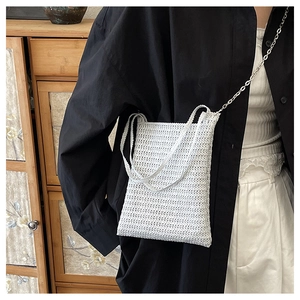 Detail of white hand-woven crochet crossbody bag with silver chain and knit texture