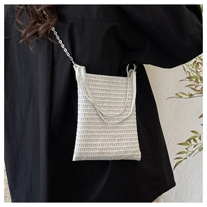 Close-up of white crochet woven shoulder bag with silver chain and textured knit pattern