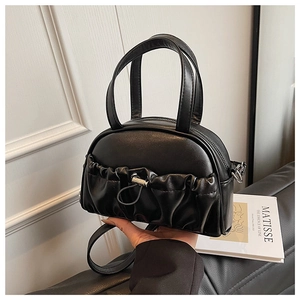 Detail of black leather handbag featuring pleated front pocket and silver drawstring buckle