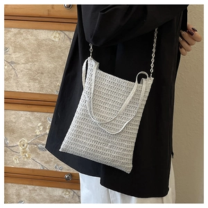 Detail of white woven bucket bag showing fine grid texture and silver chain strap