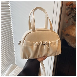 Detailed view of cream PU leather handbag with pleated front pocket and metal drawstring