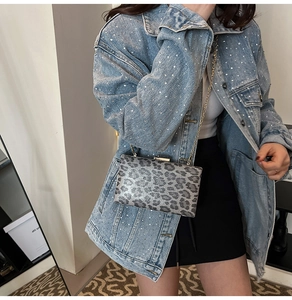 Dettaglio borsa da sera leopardata con catena dorata su giacca denim con strass
