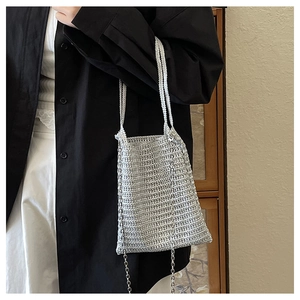Detail of silver metallic woven tote bag showing texture and metal chain strap
