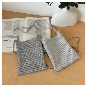 Detail of hand-woven mini crossbody bags with metallic chains and texture on a desk