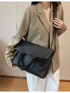 Große schwarze Leder-Tragetasche mit Lychee-Struktur, getragen von einem Modell