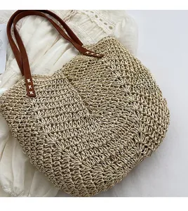 Detailed texture of hand-woven straw beach bag with brown leather handles and stitching