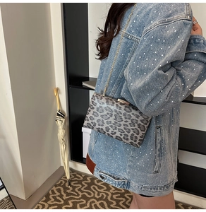 Dettaglio della pochette leopardata grigia con catena dorata e chiusura in metallo su denim