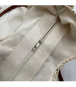 Detail view of smooth silver metal zipper and beige canvas lining inside woven tote bag
