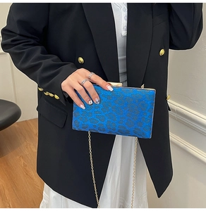 Dettaglio di borsa clutch blu leopardata con texture glitter e catena dorata