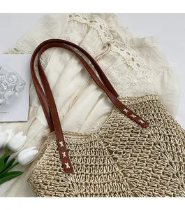 Close-up of beige straw tote bag with brown faux leather strap on lace fabric