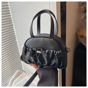 Detailed view of black pleated crossbody bag with silver drawstring lock and dual handles