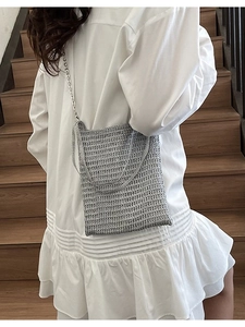 Silver woven crossbody bag with metal chain strap shown on model in natural light