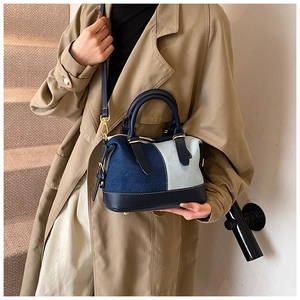 Detail of blue denim patchwork handbag with navy leather straps and gold hardware