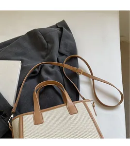 Detail of adjustable brown leather shoulder strap with gold buckle on straw tote bag