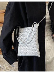 Minimalist white woven bucket bag with silver metal chain strap shown on fashion model