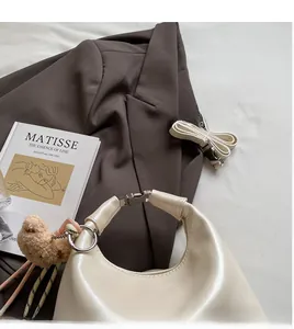 Detail of cream leather crescent bag with smooth shoulder strap and cute bear charm