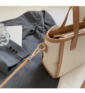 Detail of beige woven bucket bag with brown leather trim and gold metal hardware