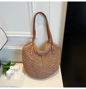 Detailed close-up of woven straw tote bag with wave pattern and brown leather straps
