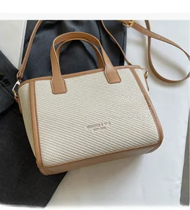 Detail view of woven tote bag in cream and brown with adjustable shoulder strap