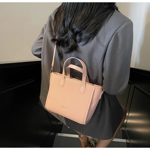 Rear view of a model wearing a pink woven handbag with Memories & Classic logo