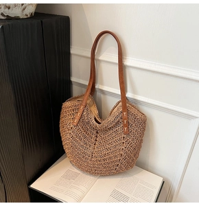 Détail du sac cabas en paille tressée avec poignées en cuir et texture ondulée