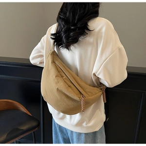 Detail of khaki crescent crossbody bag with braided zipper pull on a model