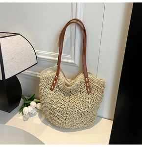 Détail du sac cabas tissé montrant la texture paille beige et la poignée en cuir marron